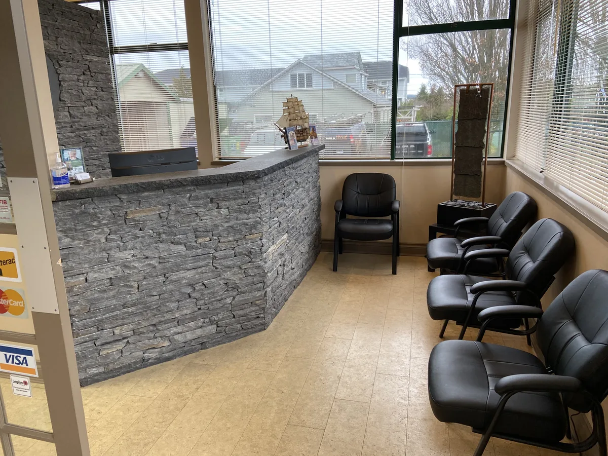 The waiting room, with leather chairs beside the slate front desk and big bright windows